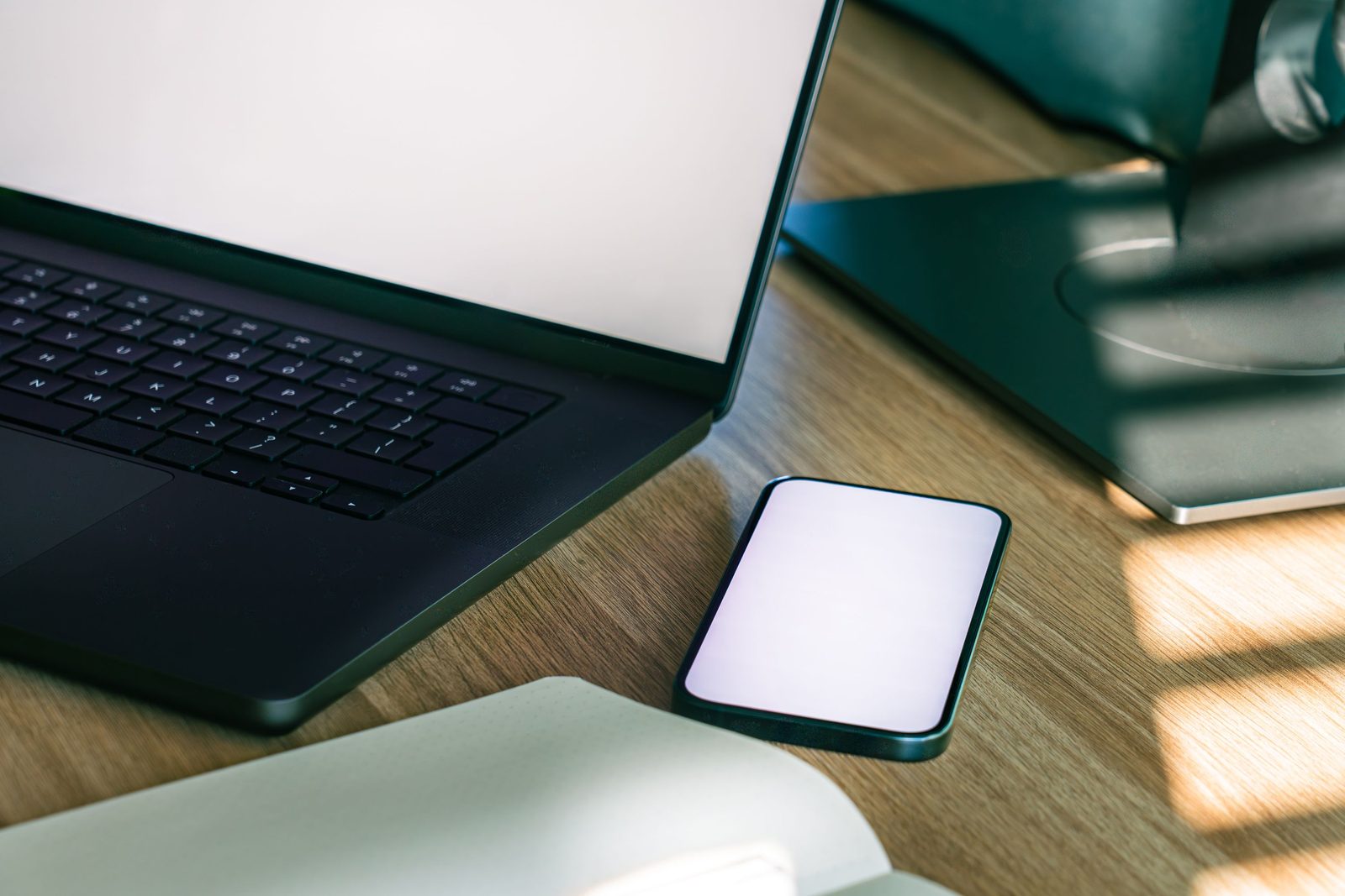 Laptop e smartphone sobre mesa, representando telefonia em nuvem e canais digitais